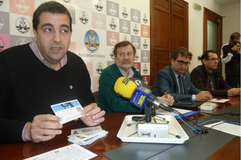 Presentació d'Alcoianada. En primer pla, Joanfran Álvarez, director de Las Esclavas, mostra una de les targetes. Li acompanyen representants de l'Ajuntament, Vectalia i la UPV. /AM