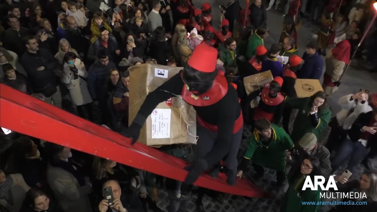 Patges pujant regals als xiquets per l'escala durant la cavalcada dels Reis Mags d'Alcoi