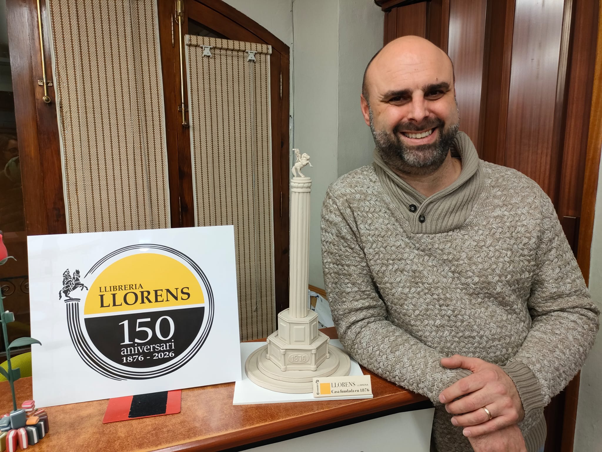 José Ernesto Nadal, actual propietari, junt al logo de la llibreria i una rèplica de la columna.